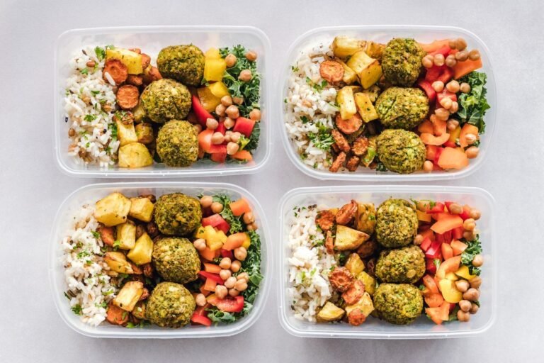 Colorful meal prep containers with falafel, chickpeas, rice, and vegetables