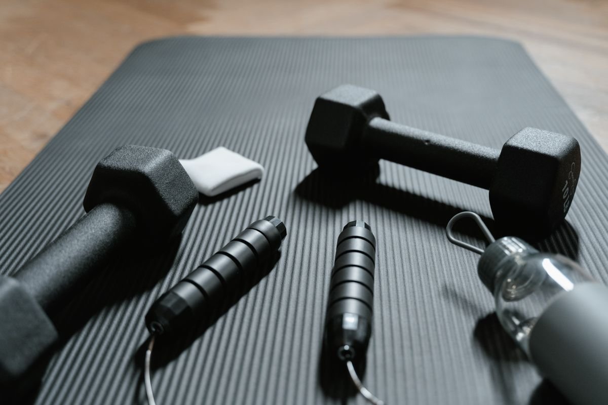 Close-up of dumbbells, jump rope, and water bottle on a yoga mat
