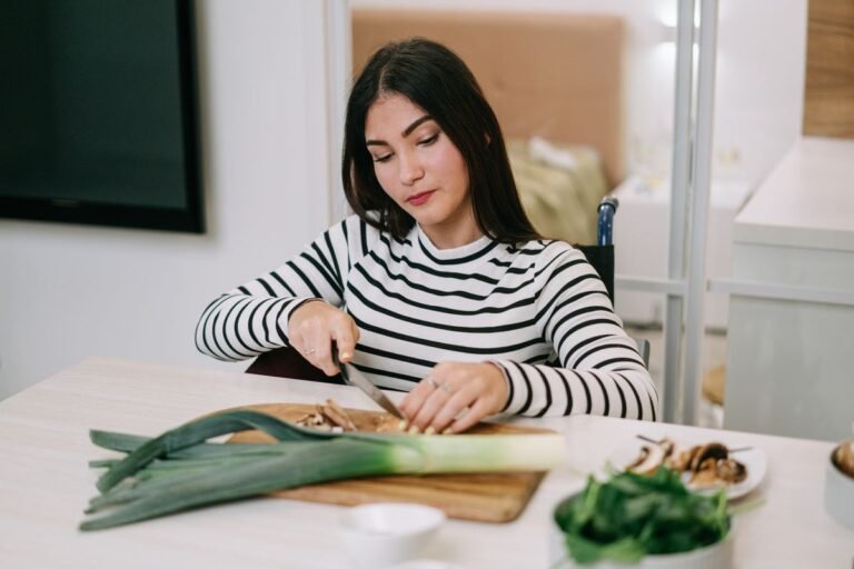 A woman in a striped shirt slices leeks on a kitchen counter