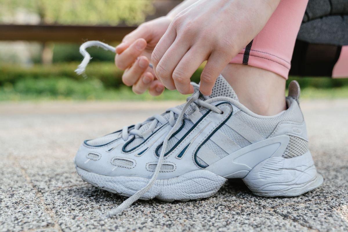 Close-up of a woman tying shoelaces on white sneakers during an outdoor exercise session